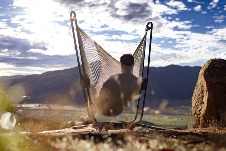 Man swinging in a Yellow Leaf Hammock Chair, overlooking a desert landscape.