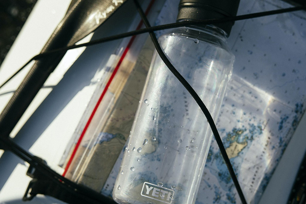 Yeti Yonder Water Bottle strapped to the deck of a kayak with bungee cords.