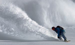 A man snowboarding with a rip of powder behind him.