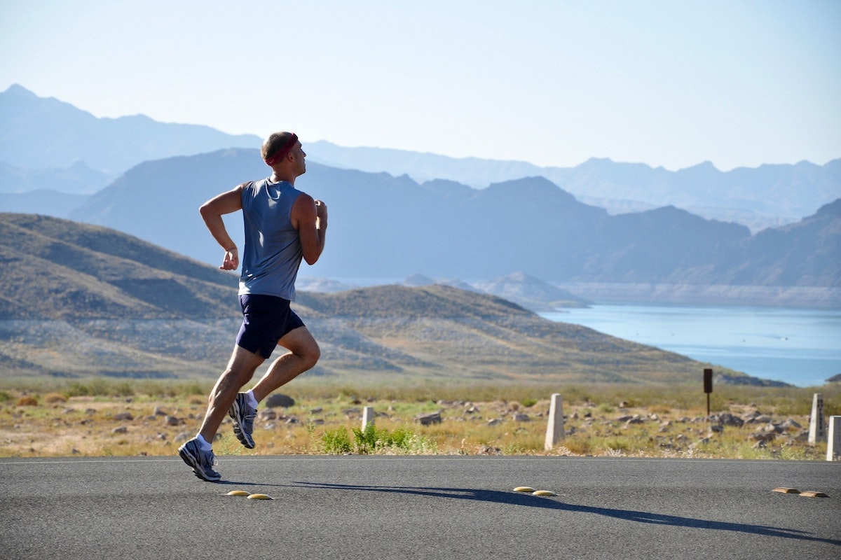 Man running by mountains on a road