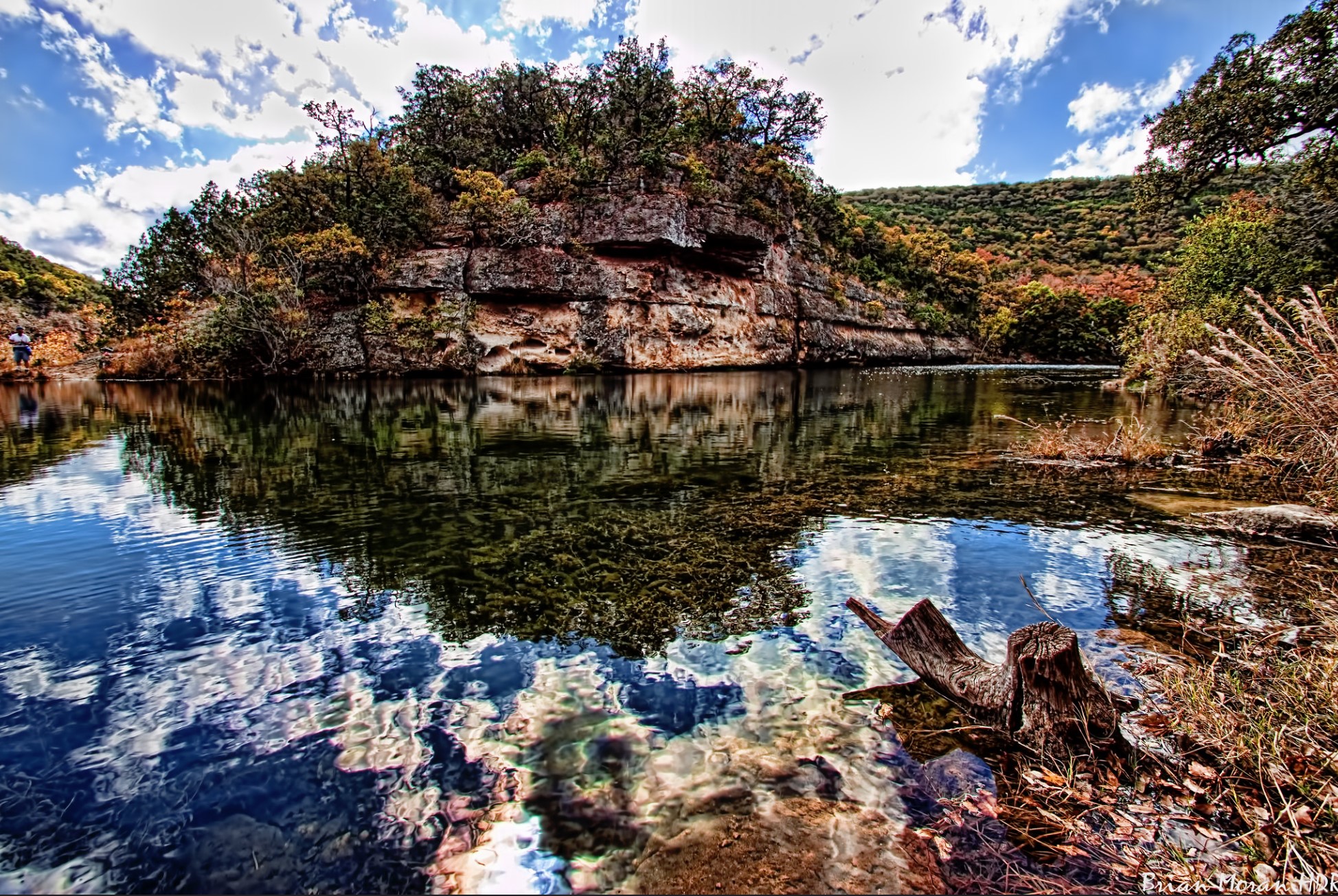 A beautiful view of Lost Maples State Park with Limestone bluffs along a clear river with a vivid reflection