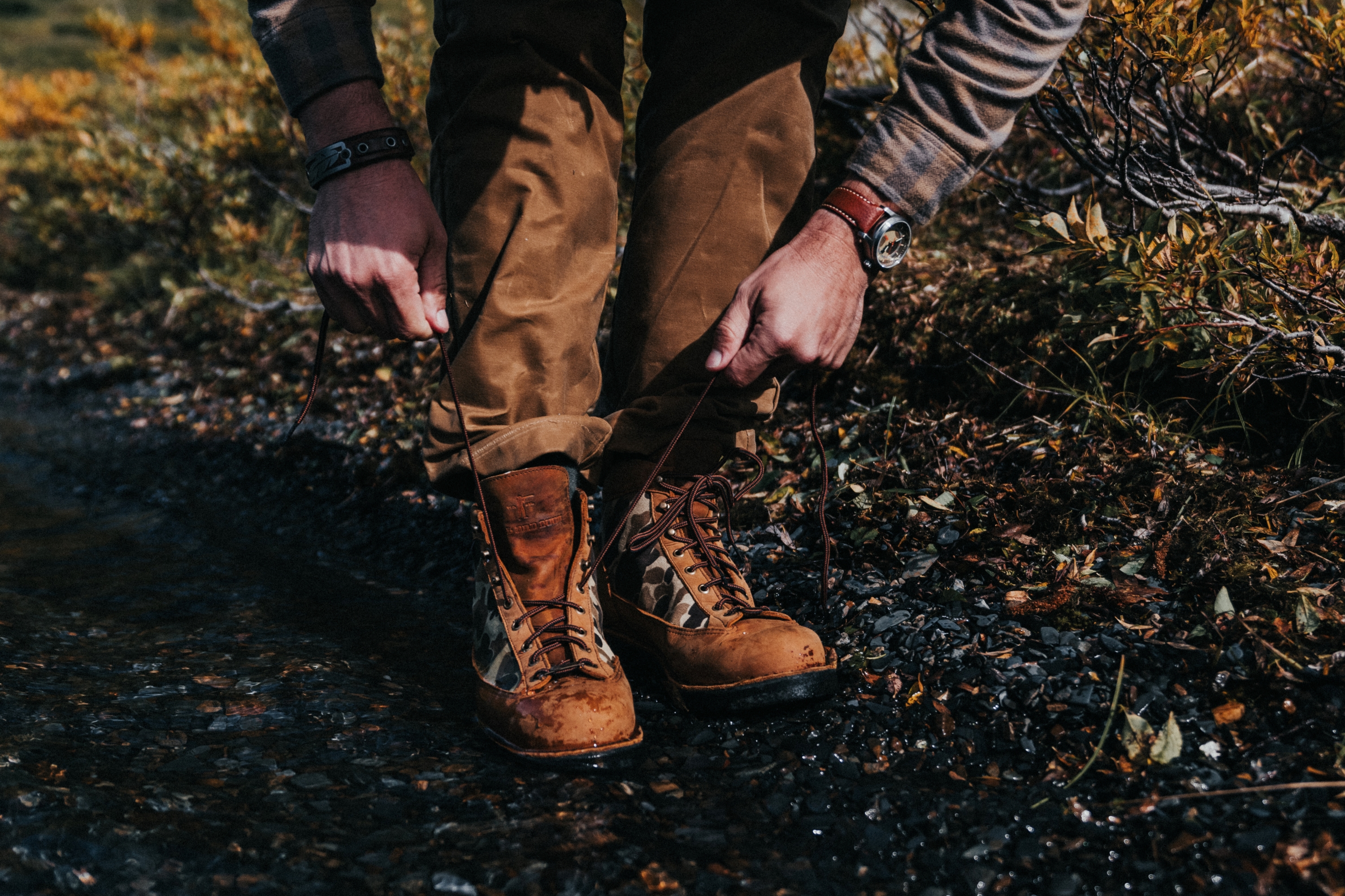 Man tying boot with Luminox watch