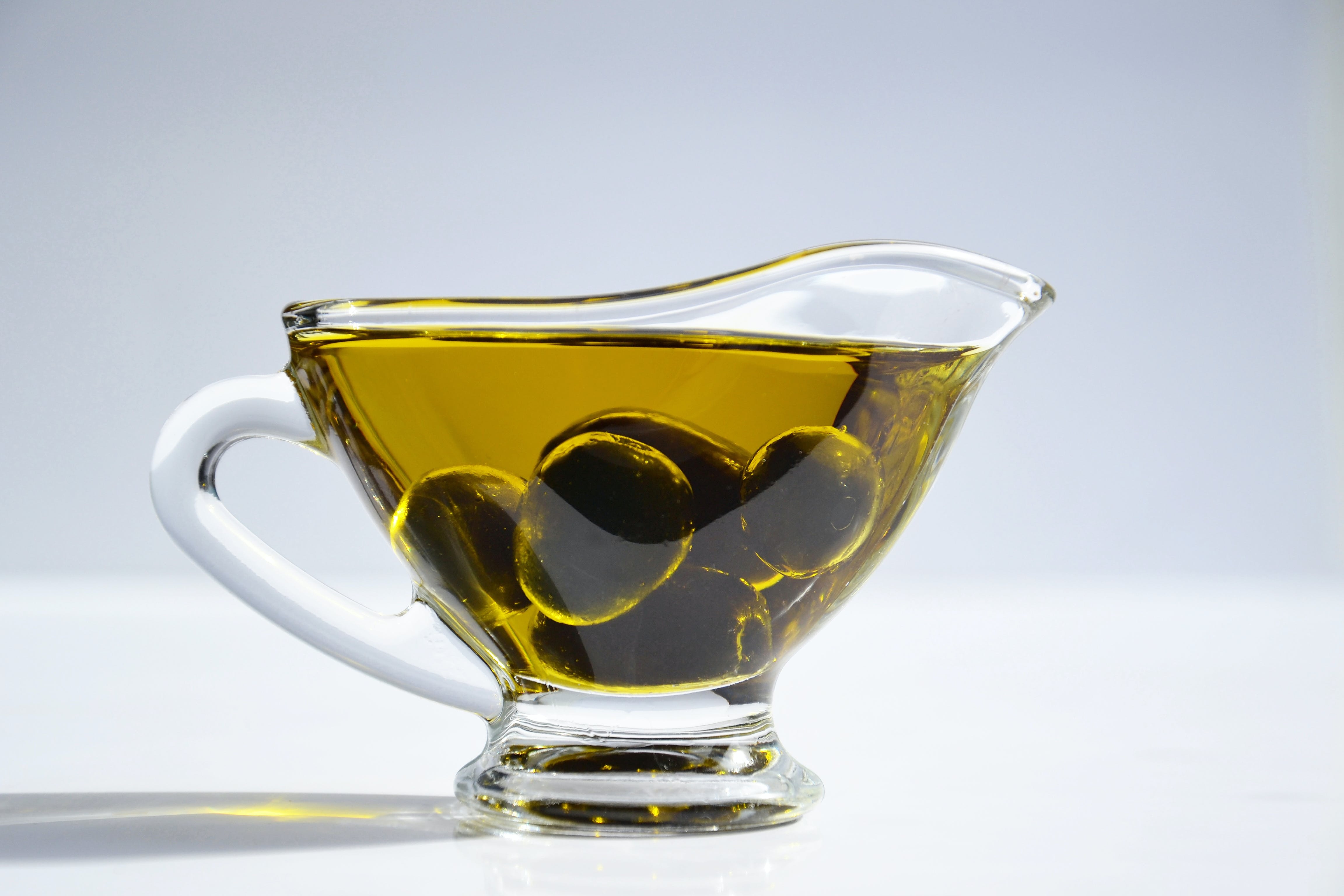 Glass cup with olive oil and olives