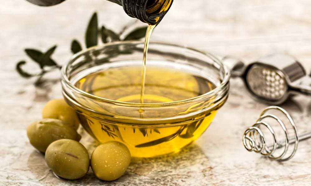 Olive oil being poured into glass jar