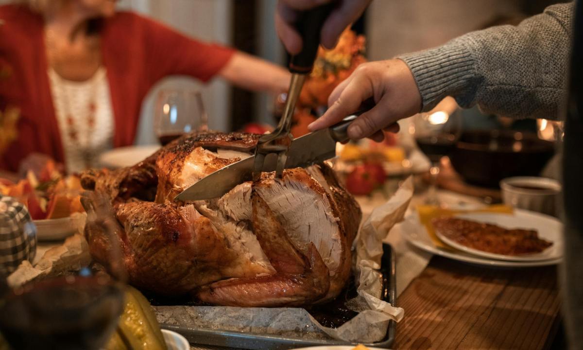 Person carving turkey at Thanksgiving table