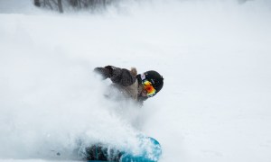 Snowboarding riding powder with red goggles