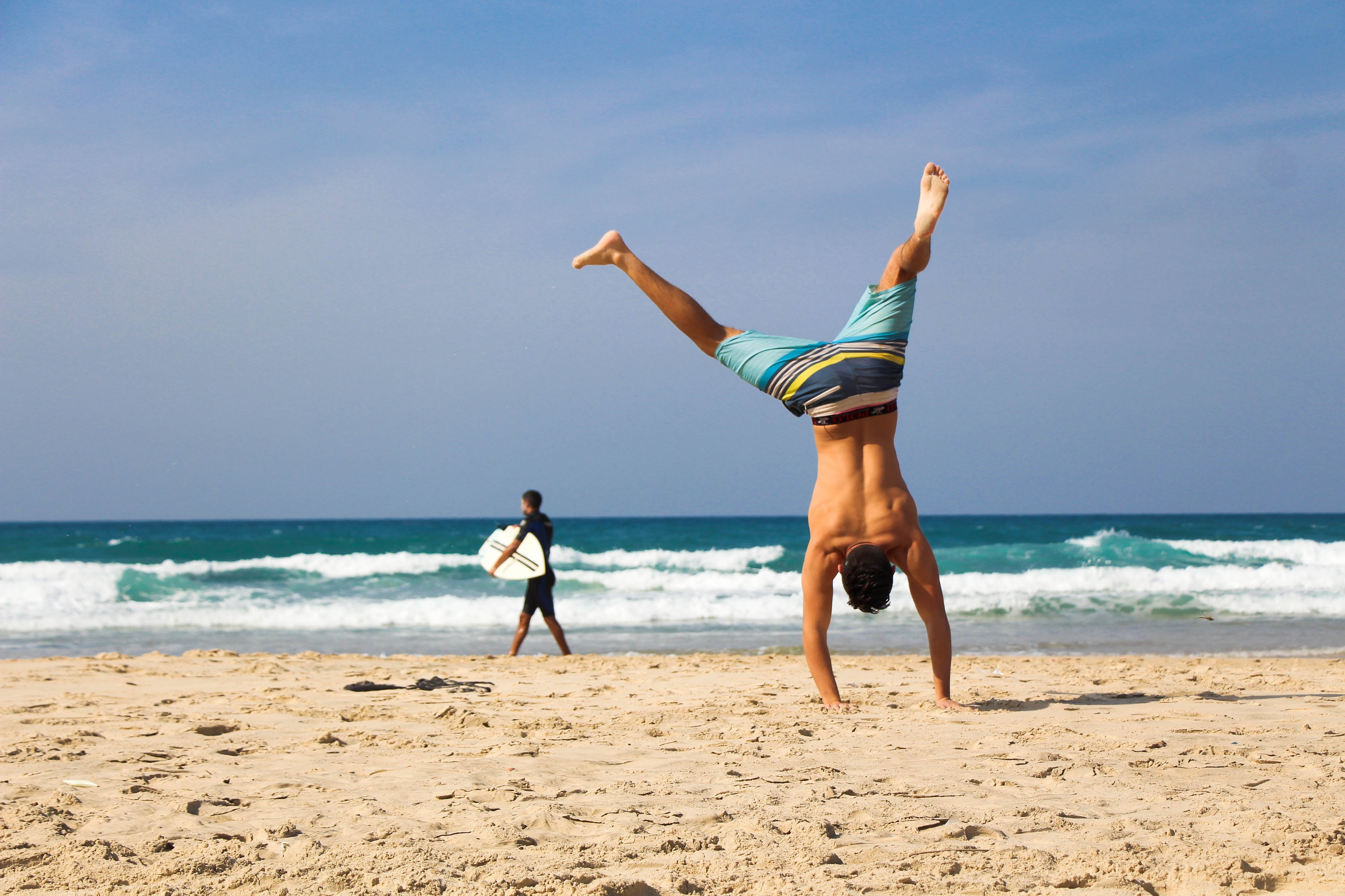 A man doing a handstand on the sandy beach