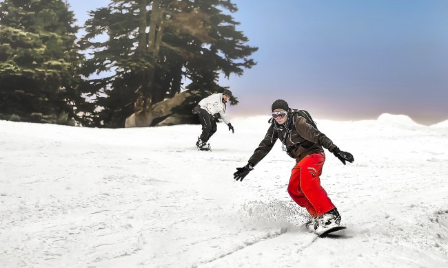 Snowboarders riding through powder