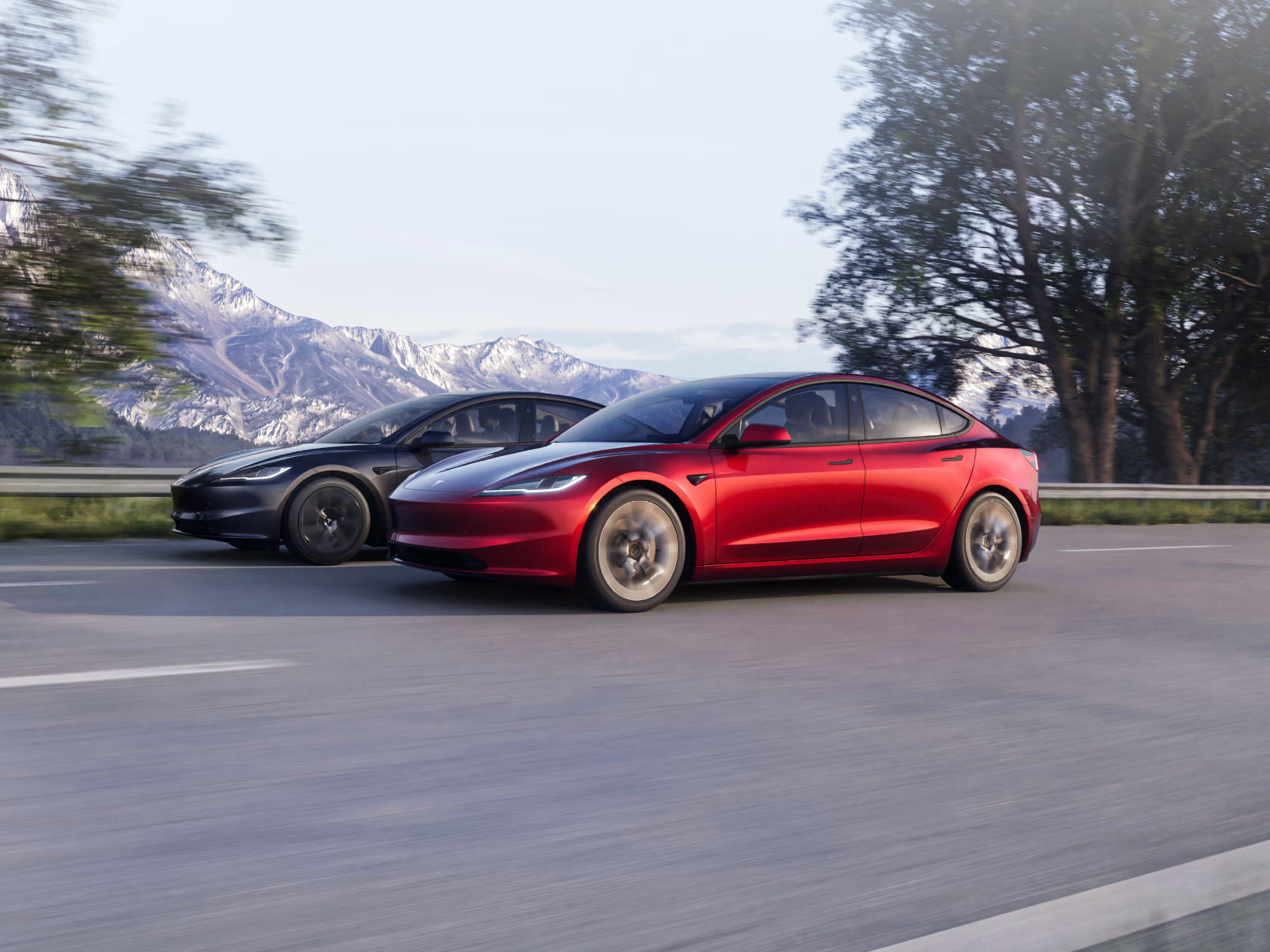 Tesla Model 3 Highland refresh two cars, one red one gray, both headed the same way on a highway.