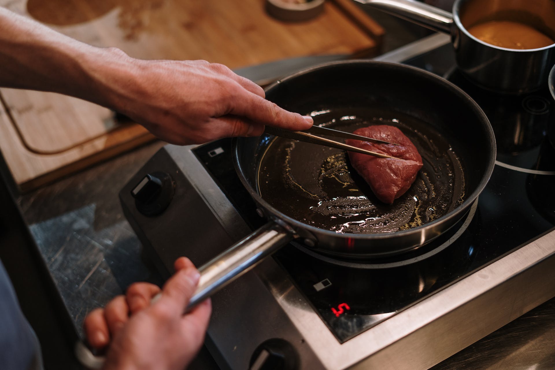 Person cooking a steak in a pan