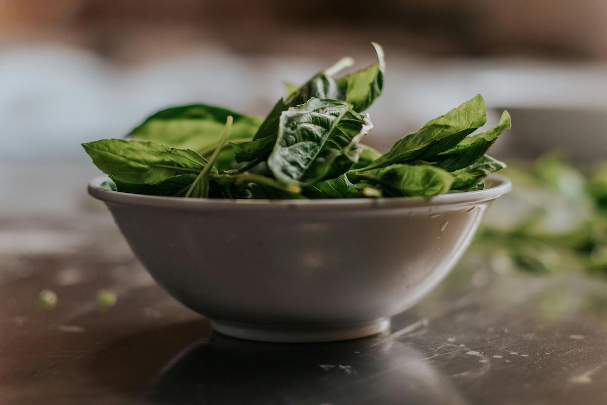 A bowl of spinach on a wood table