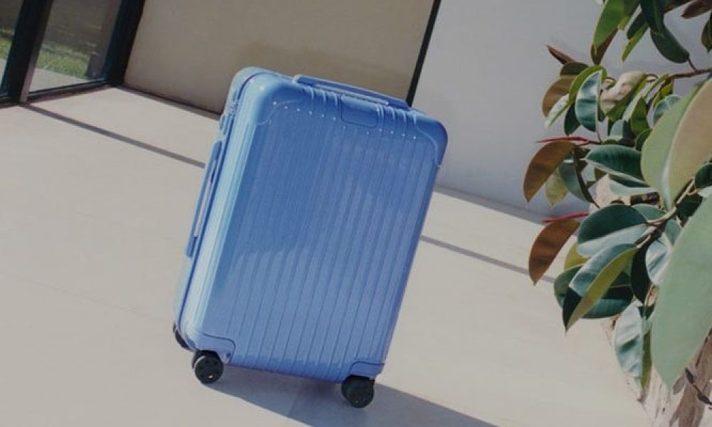 The Rimowa Sea Blue luggage placed next to a plant outside.