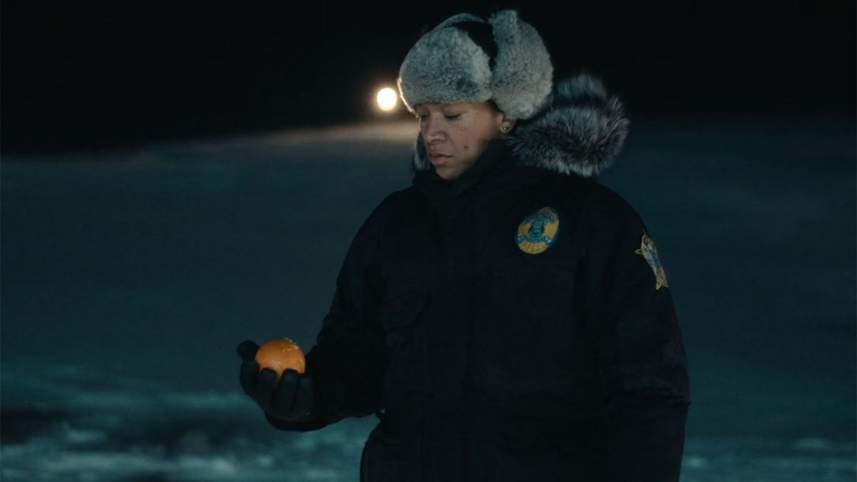 Kali Reis holds an orange in True Detective: Night Country.