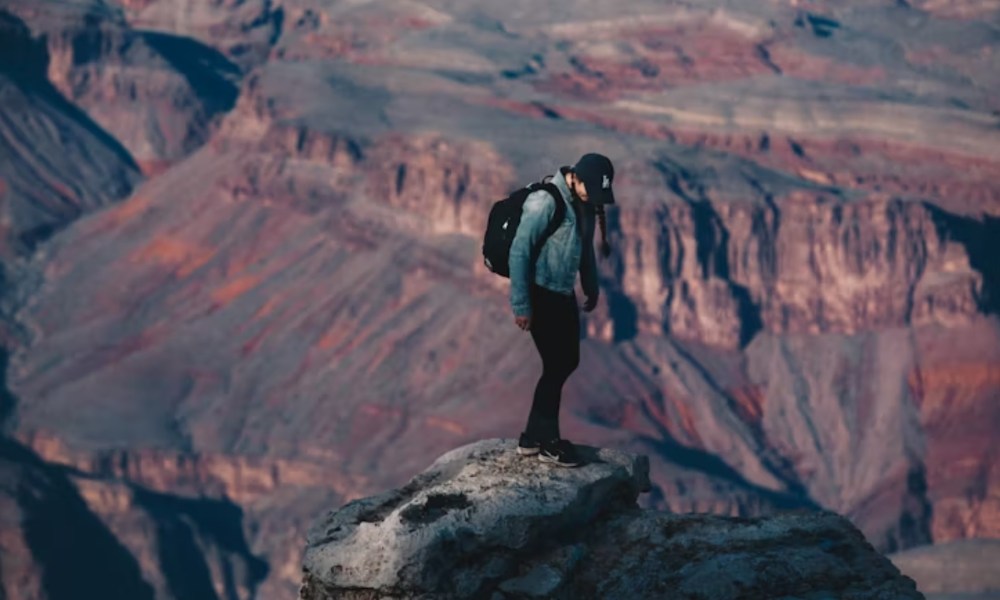 a man standing on a stone pillar in Grand Canyon National Park