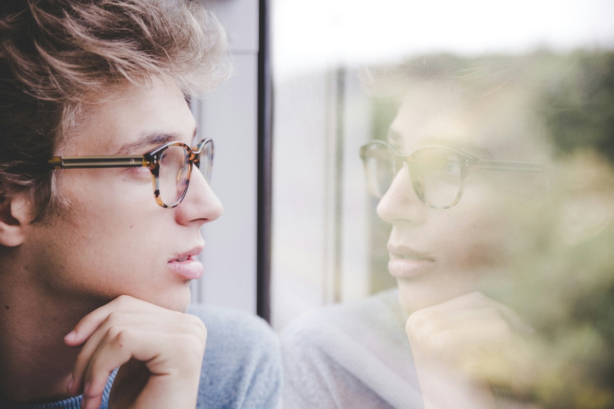 a man looking at his reflection in the window