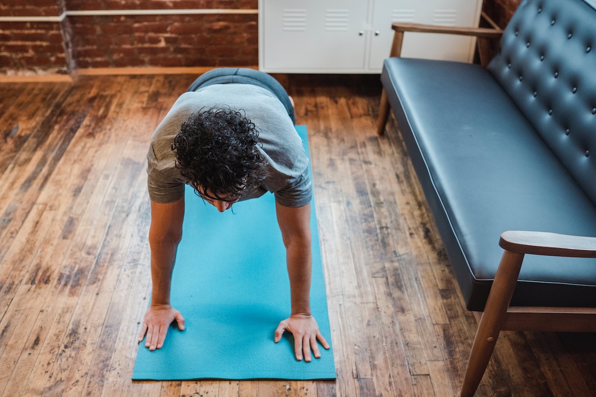 A man on a bright blue mat doing a plank