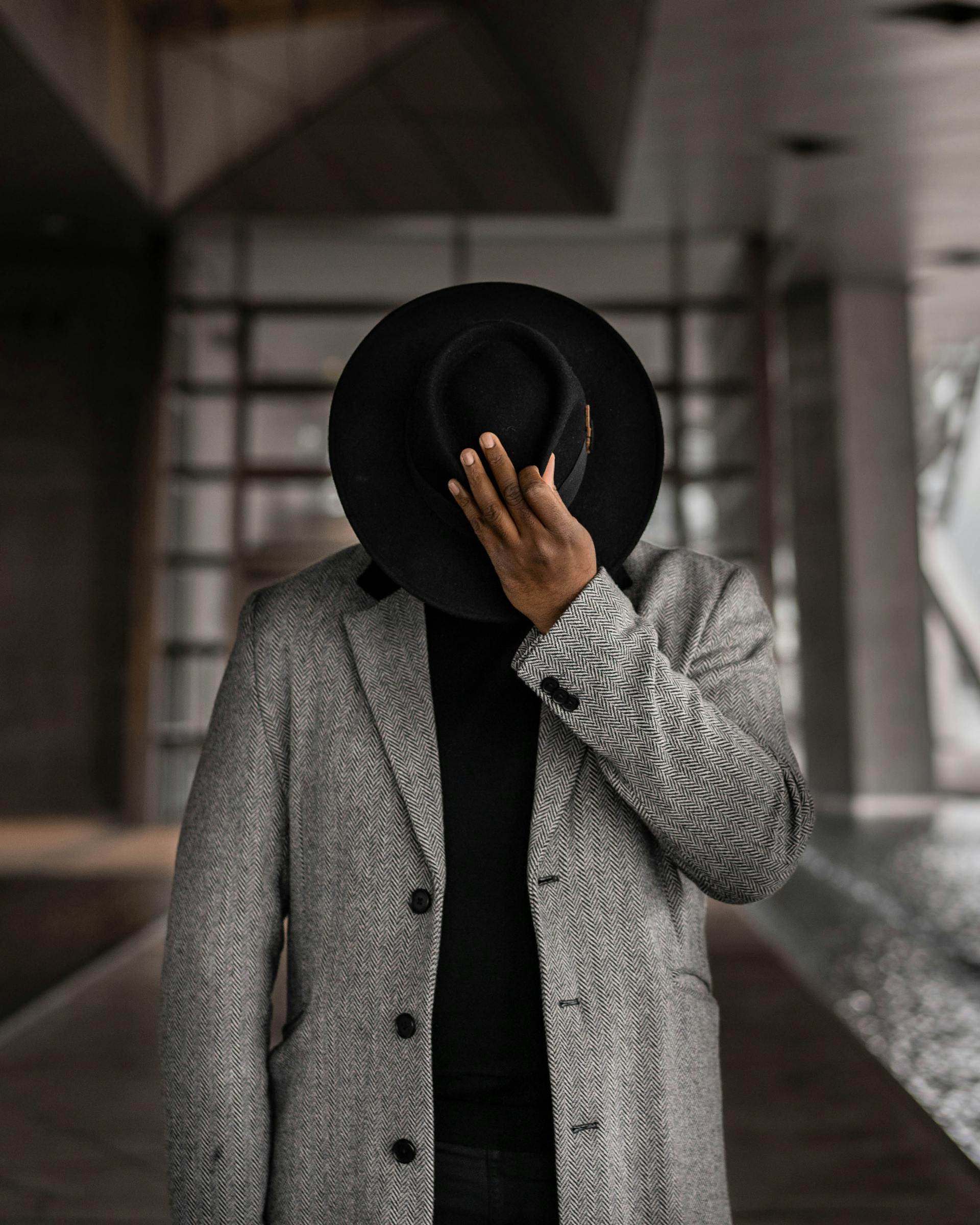 man wearing tweed coat and holding hat