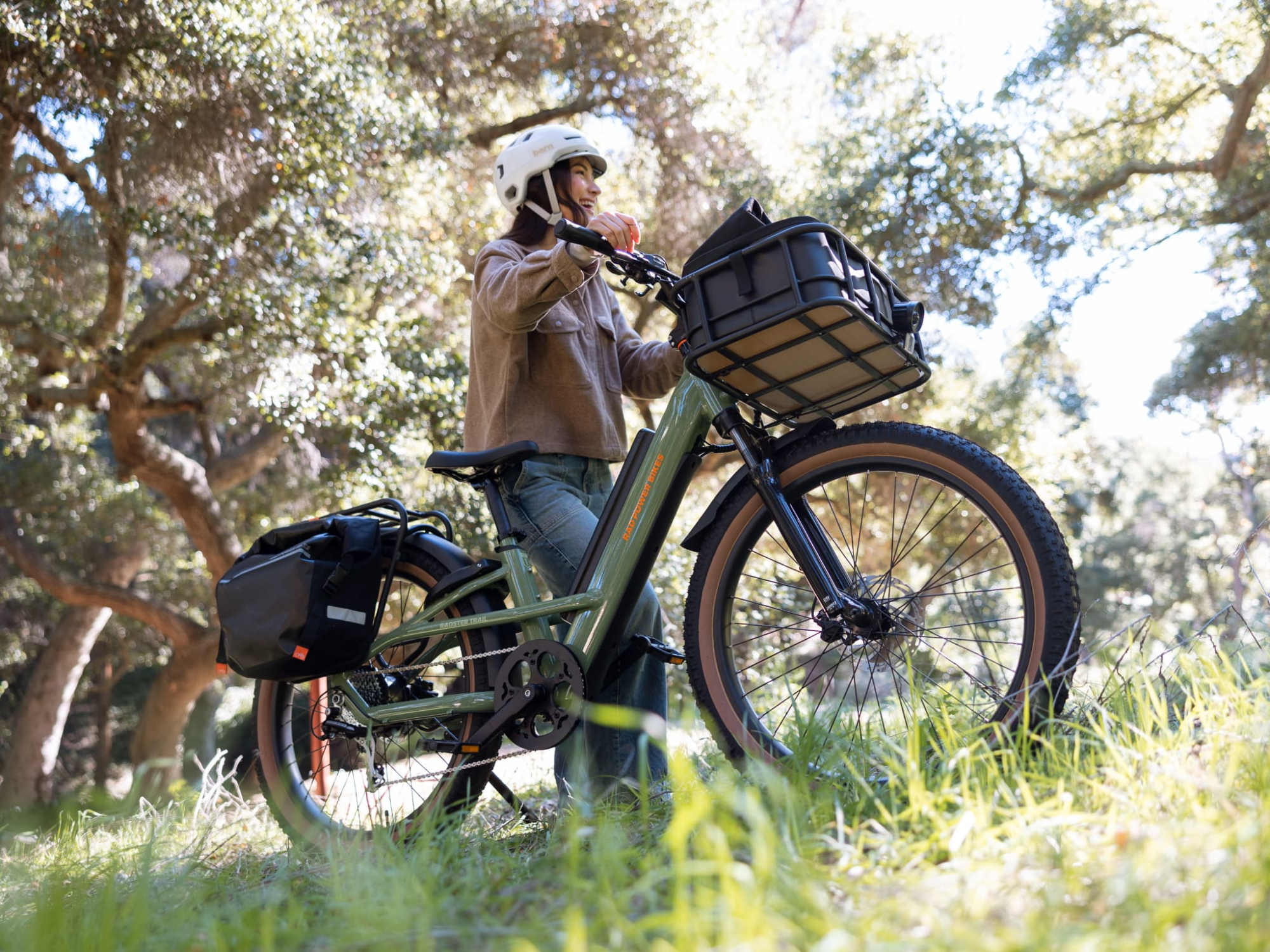 A rider standing next to a Rad Power Bikes Radster Trail e-bike on a grassy hillside.