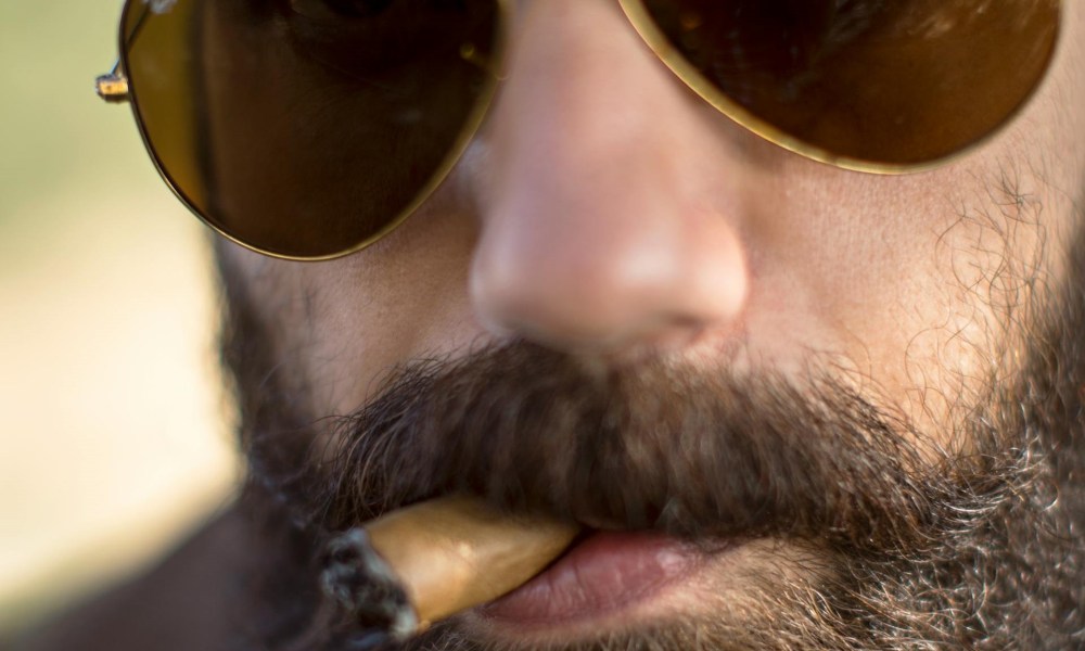 Close-up of bearded man smoking a cigar almost done