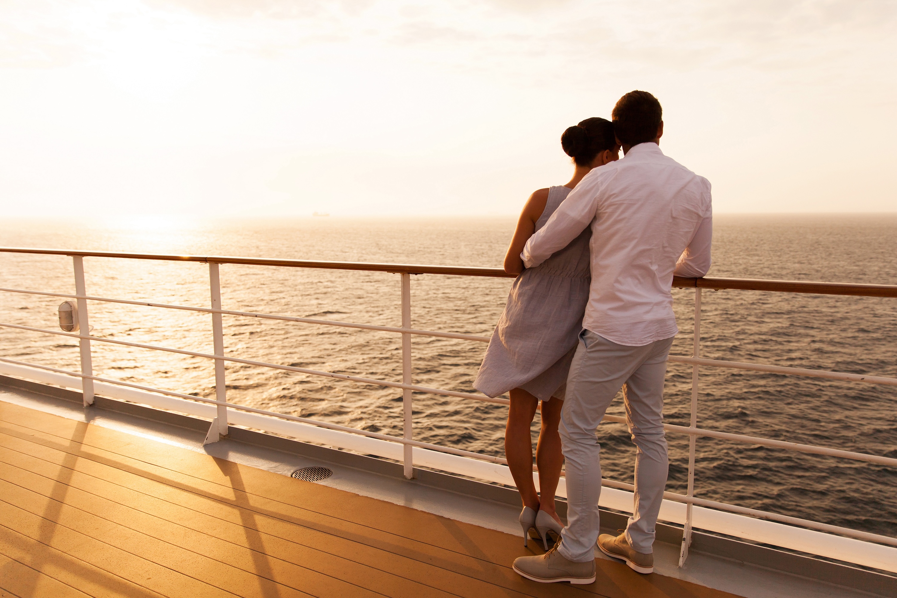 back view of young couple hugging at sunset on cruise ship