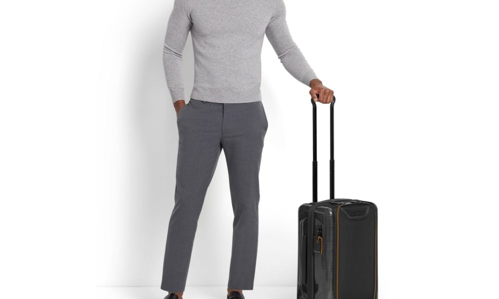 Man holding Tumi luggage by the handle.