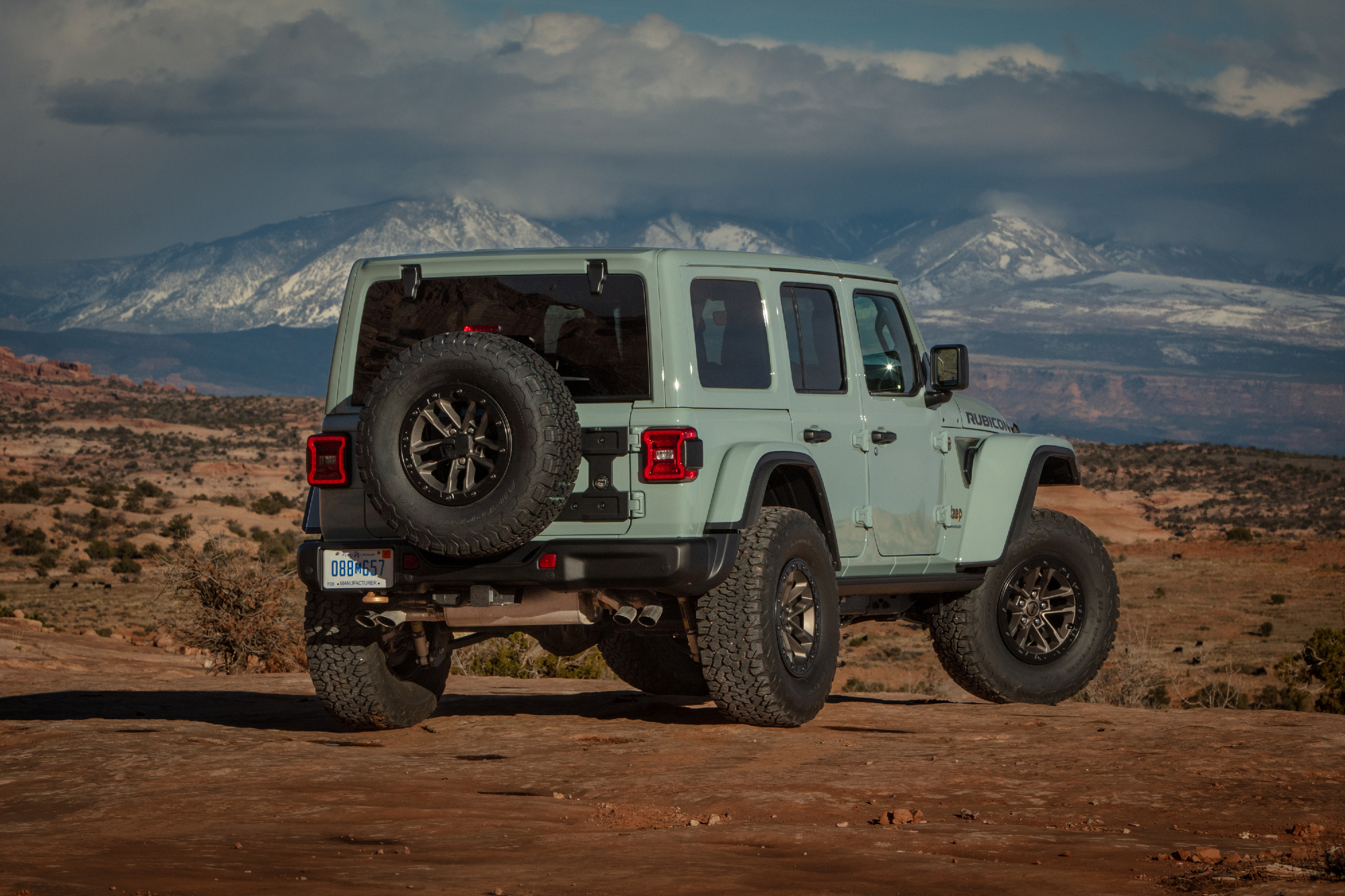 Light blue 2024 Jeep Wranger Rubicon 392 Final Edition parked on a desert road with snow covered mountains in the far background.