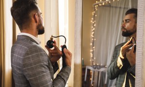 Handsome bearded man is using atomizer nozzle with perfume