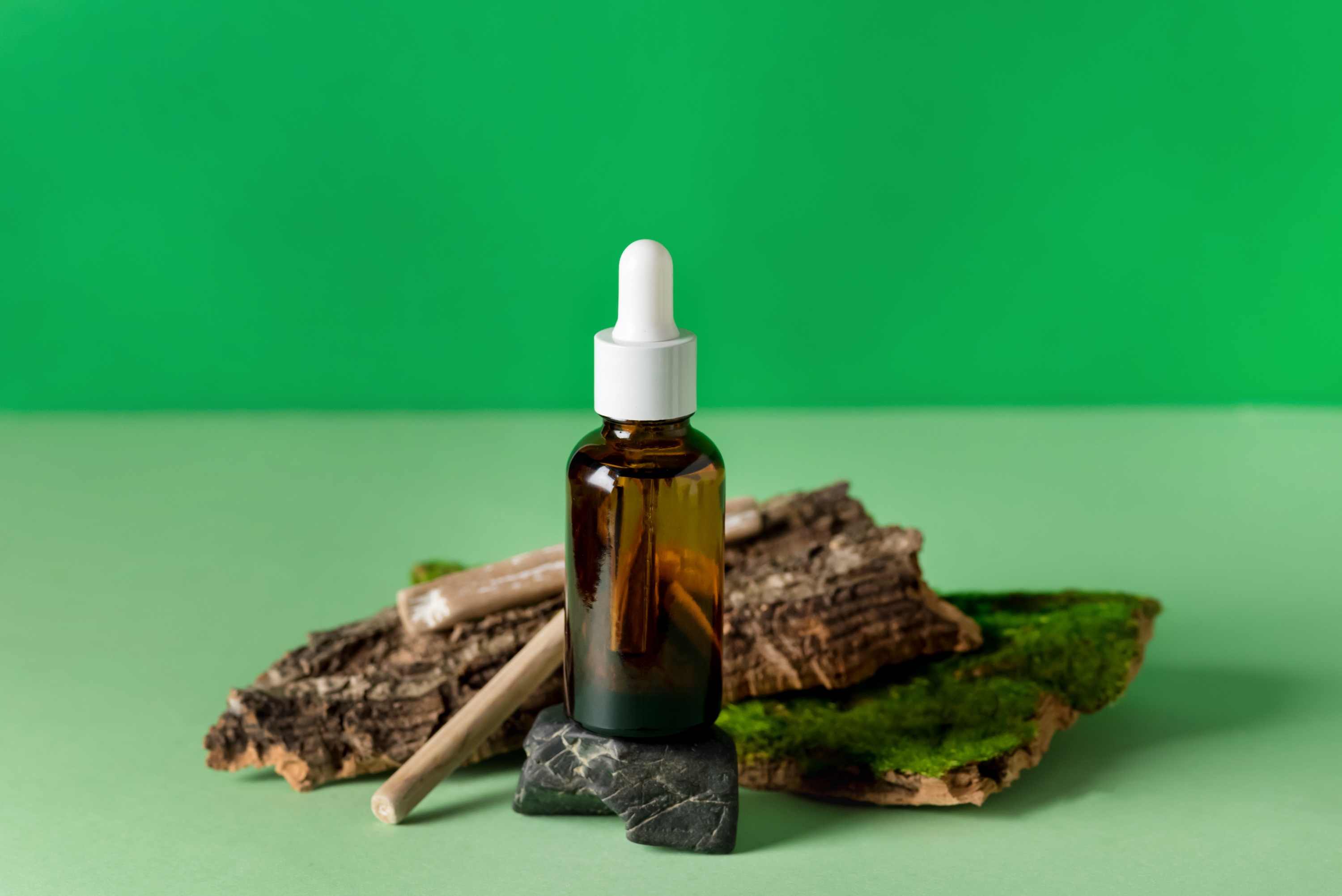 Serum Glass Bottle Green Background Composition with Natural Materials: Tree Bark, Stones Wooden Sticks Health and Natural Care Cosmetics Concept