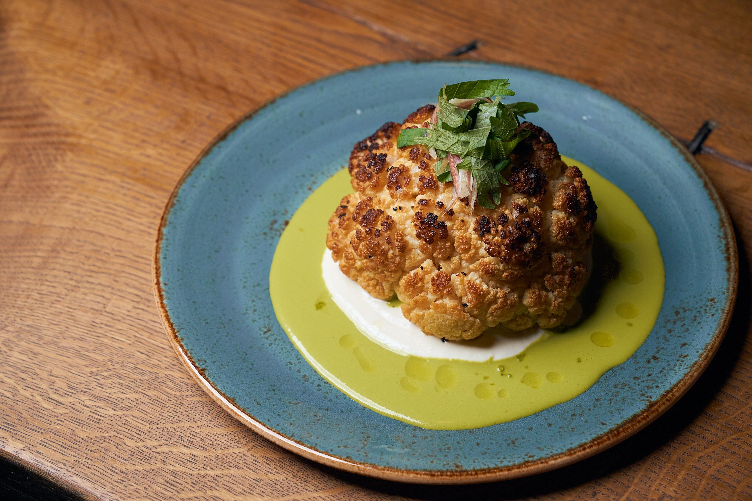 whole roasted cauliflower on blue plate