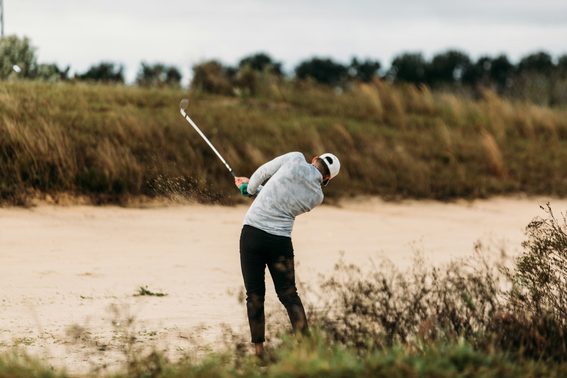 man golfing near sand