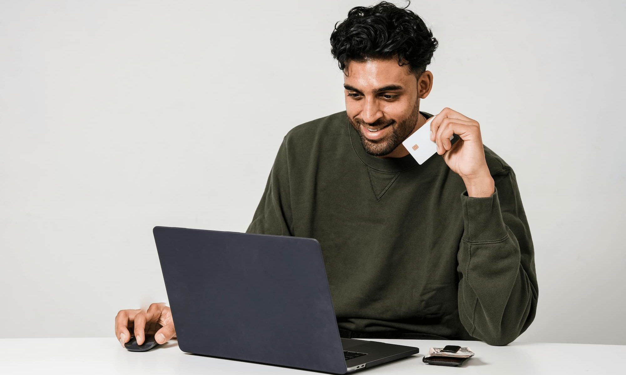 man holding credit card looking at computer