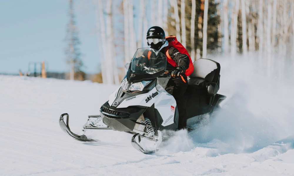 Person snowmobiling at high-speed on a Ski-Doo snowmobile.