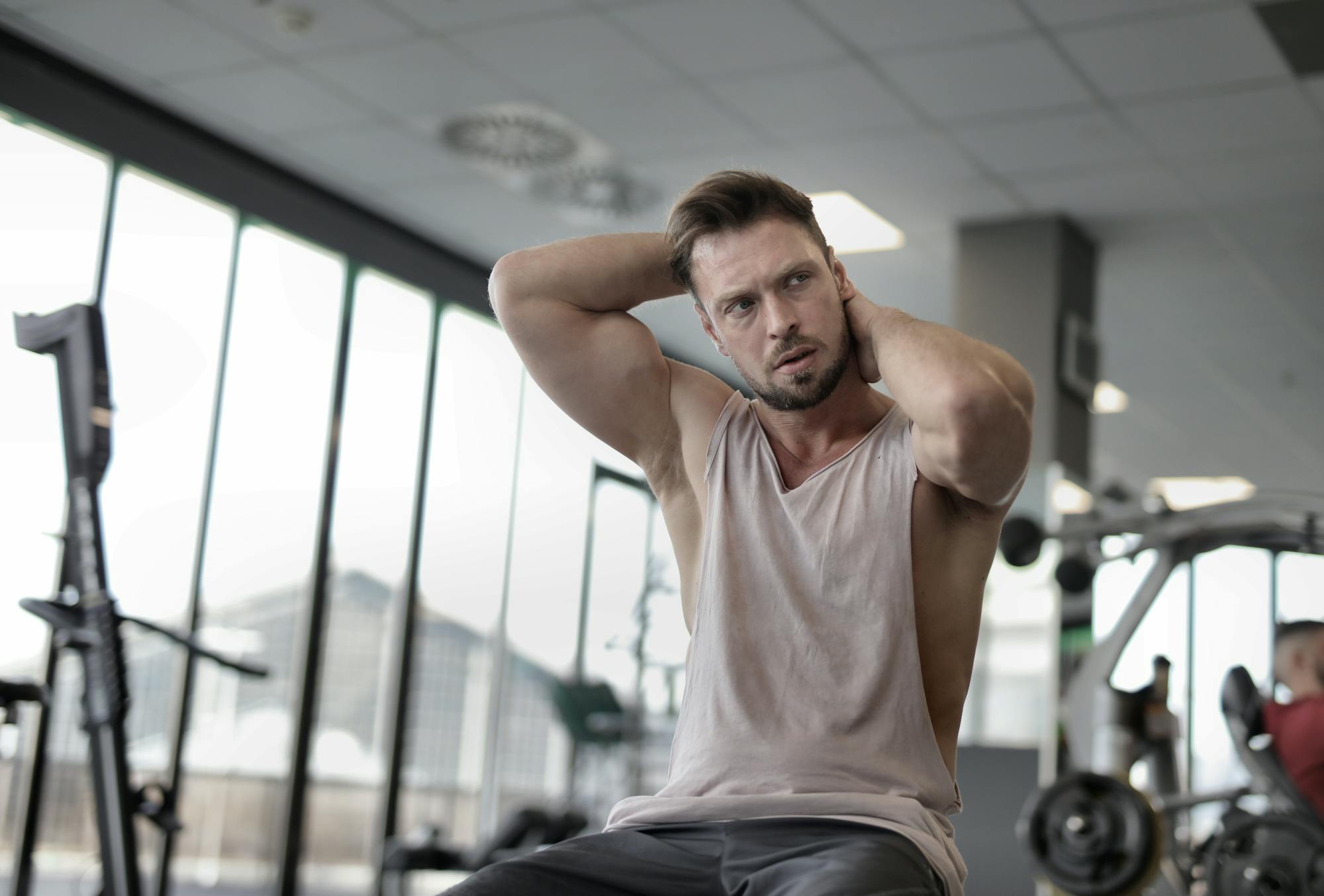 man sitting in gym wearing vest or tank top flexing biceps
