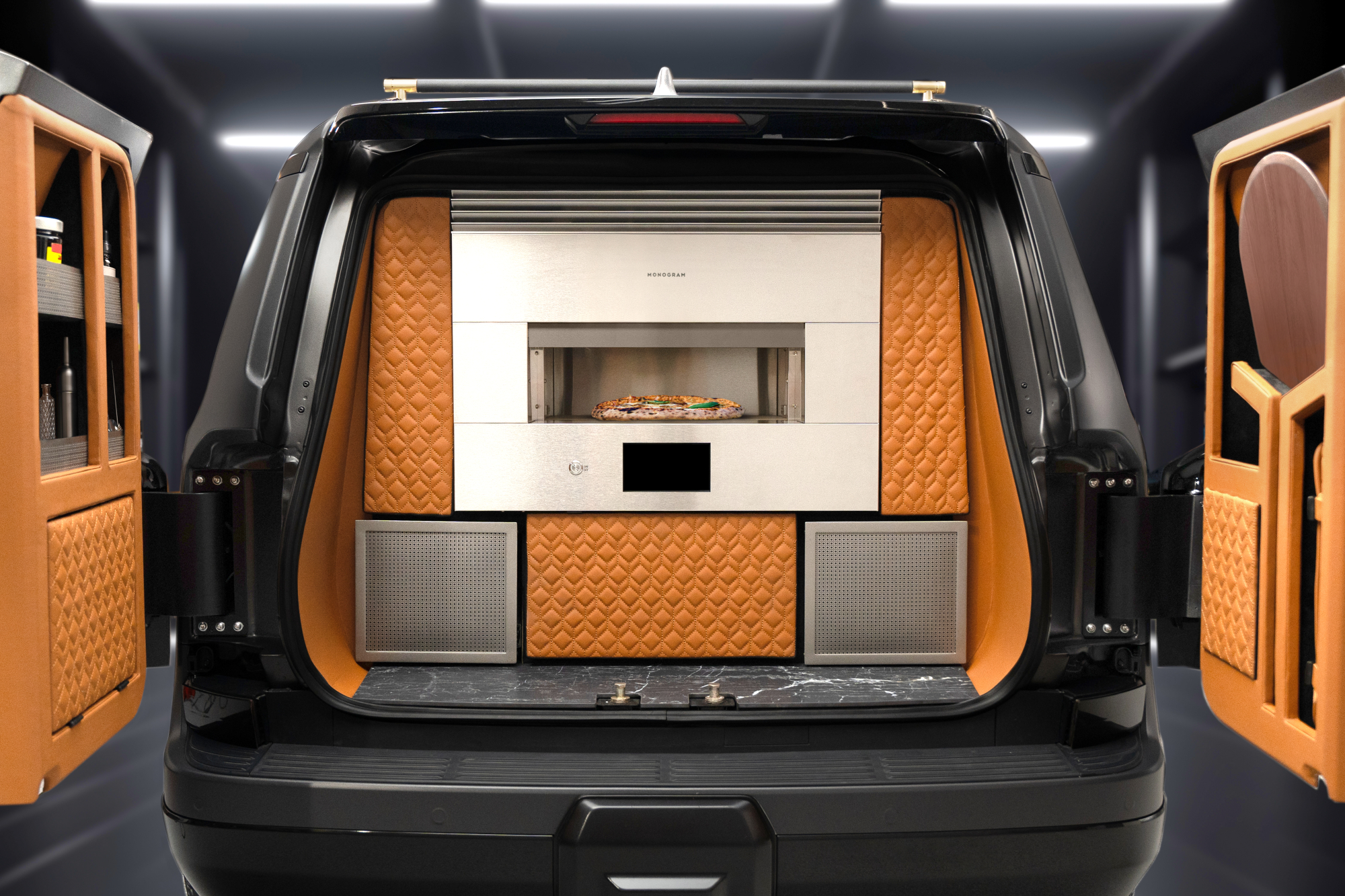 2024 Lexus Monogram GX concept vehicle rear view with doors open revealing pizza oven and bar.