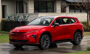 2025 Toyota Crown Signia Limited Finish Line Red in the rain parked on a driveway in front of a house.