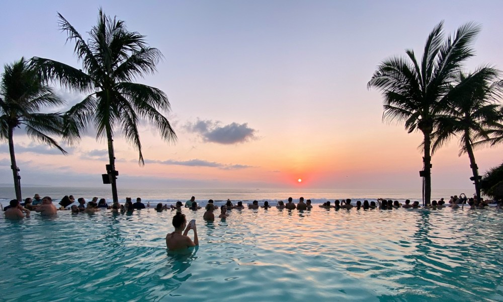 People in a pool watch the sunset in Bali