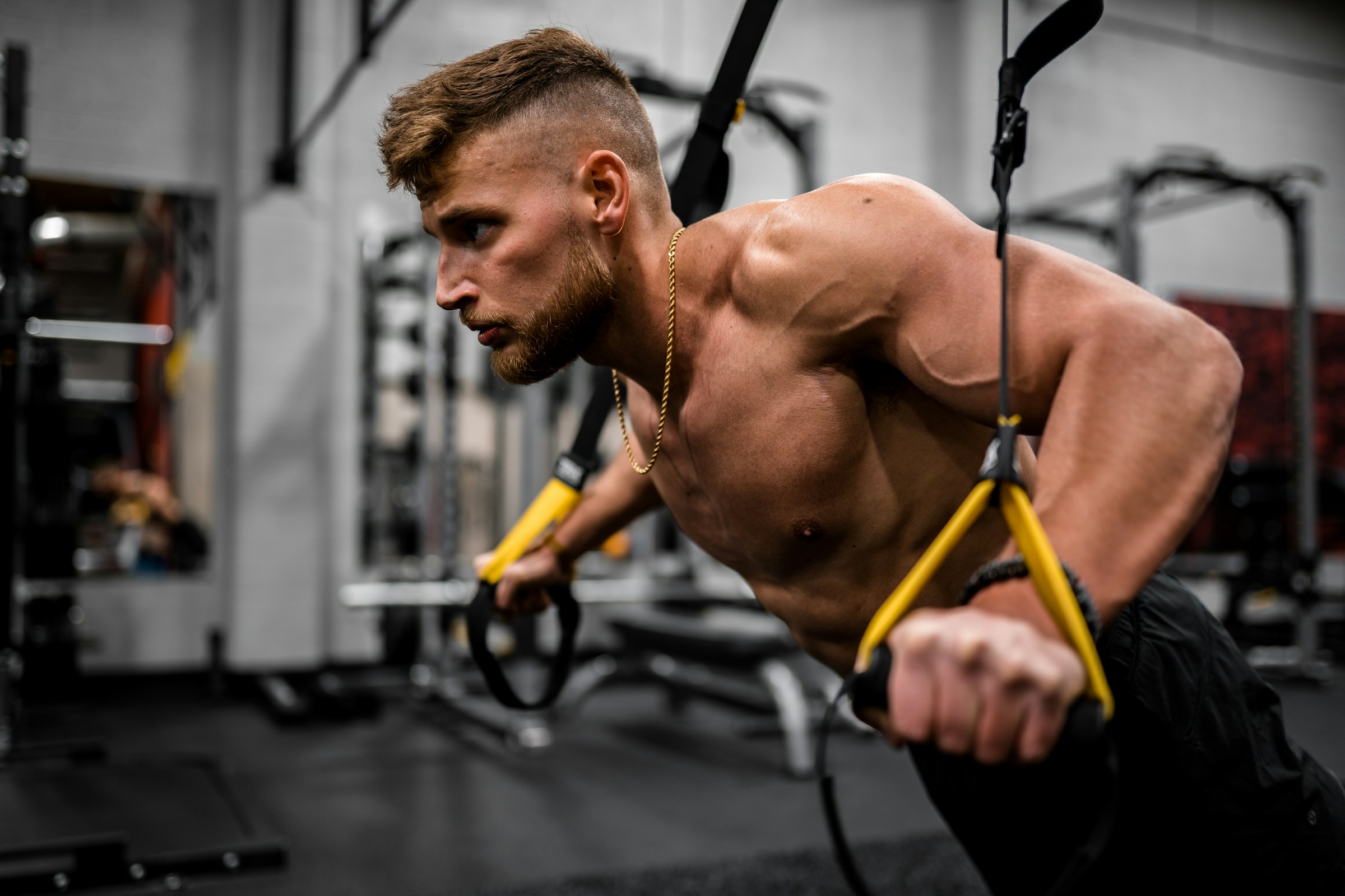 shirtless man with cable machine doing rear delt fly reverse fly with cable machine in gym-