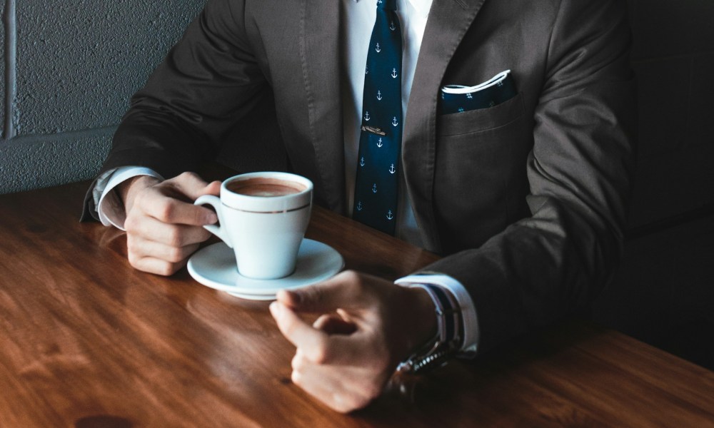 man sitting at table drinking coffee