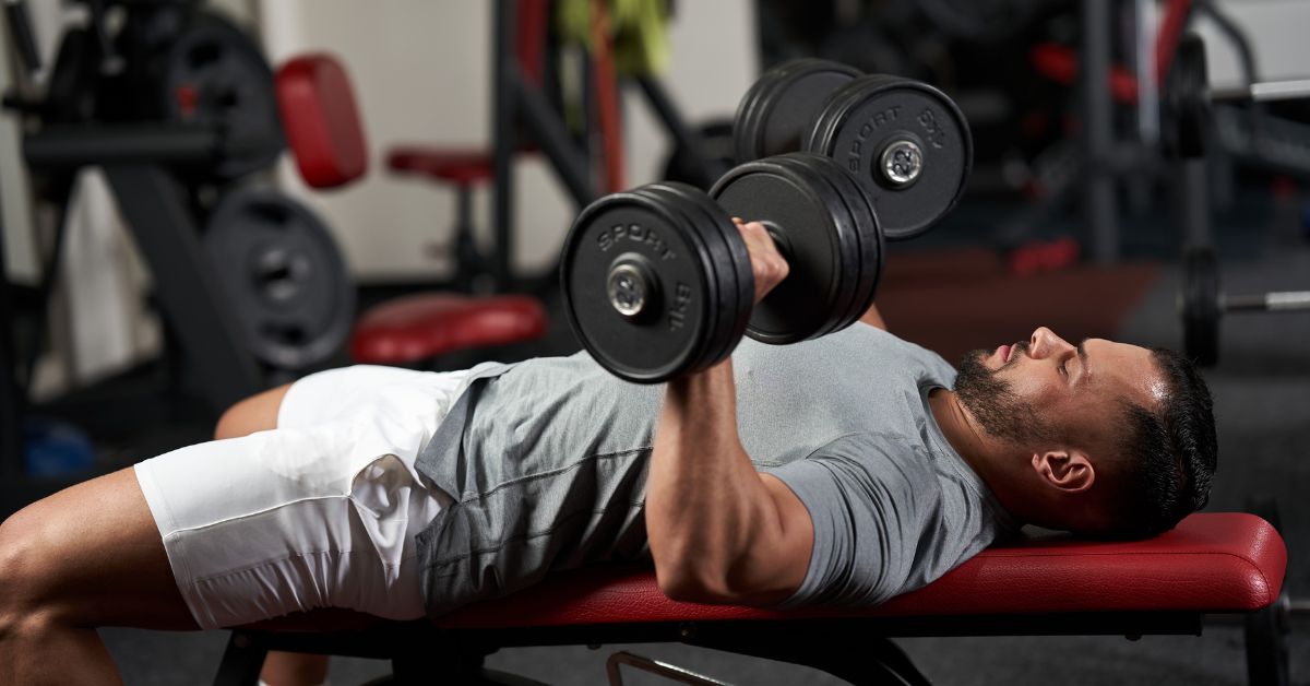 man on red wright bench lifting weights 