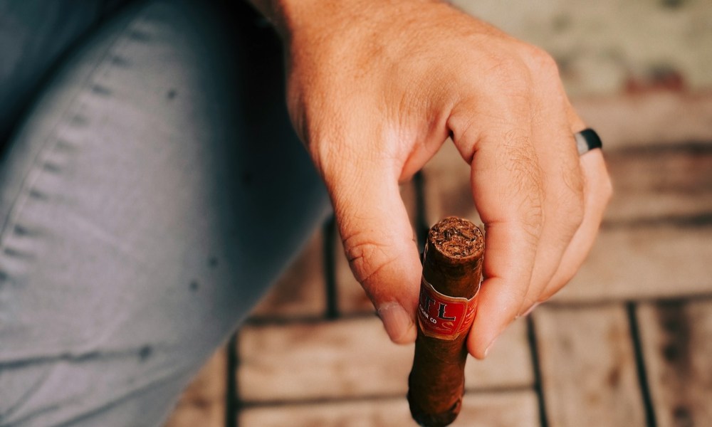 Man holding lit cigar relaxing.