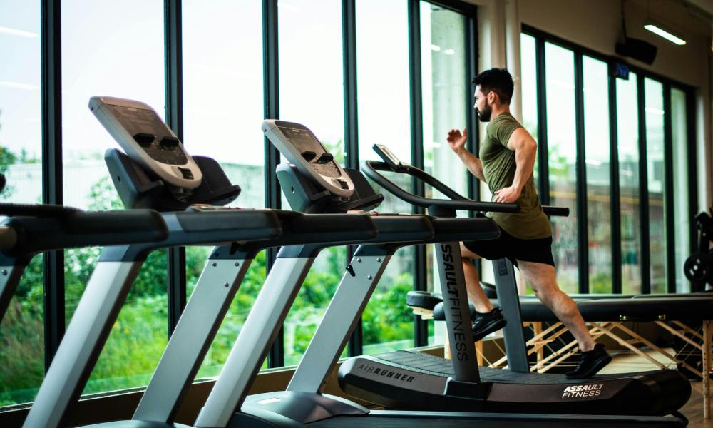 Man on a treadmill in front of windows