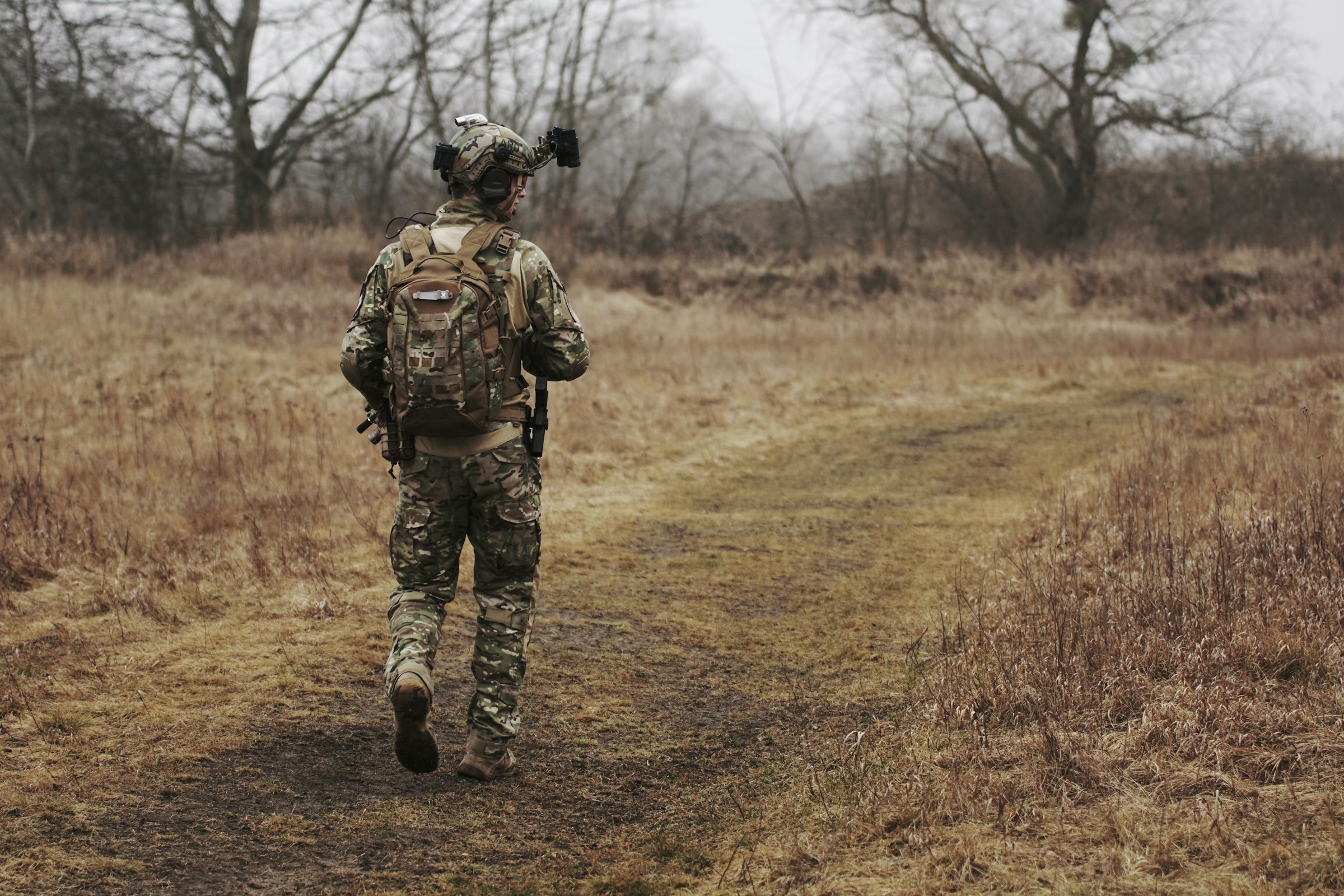 military man army man wearing backpack or rucksack hiking through woods or forest
