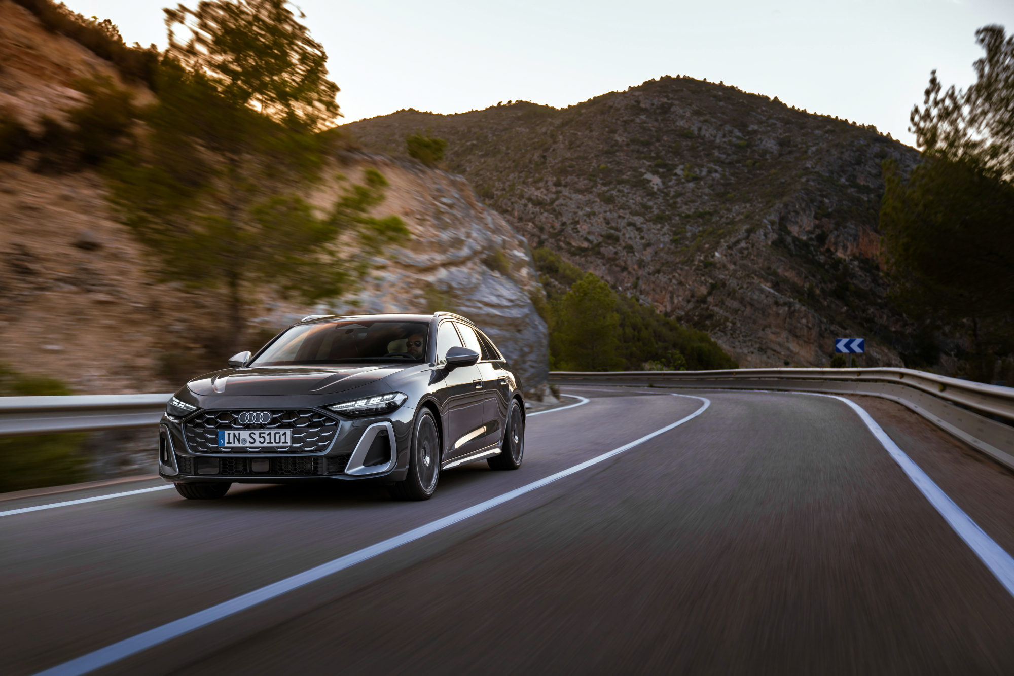 2025 Audi A5 left front three-quarter frontal view driving on a highway in the mountains.