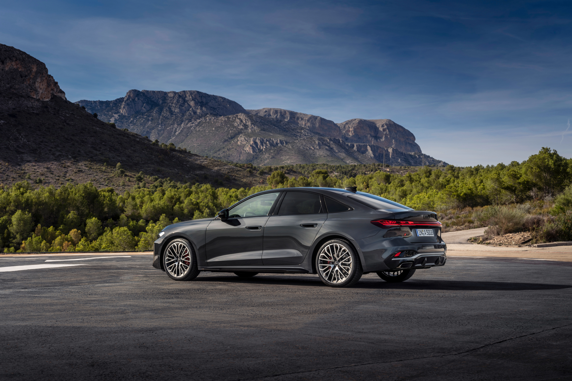 2025 Audi A5 left left side profile view parked on asphalt with mountains in the background.