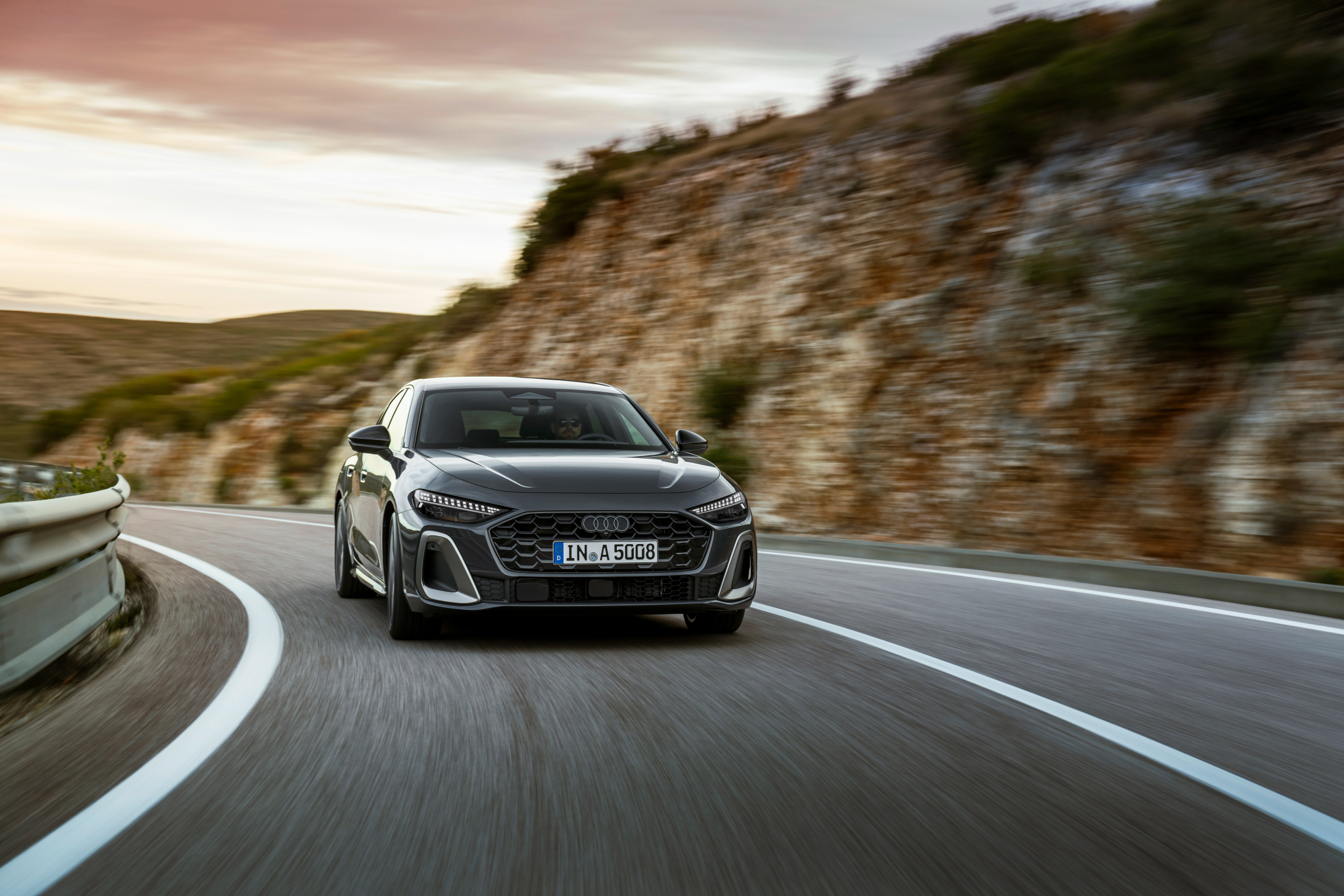 2025 Audi A5 right front frontal view driving on a highway in the mountains.