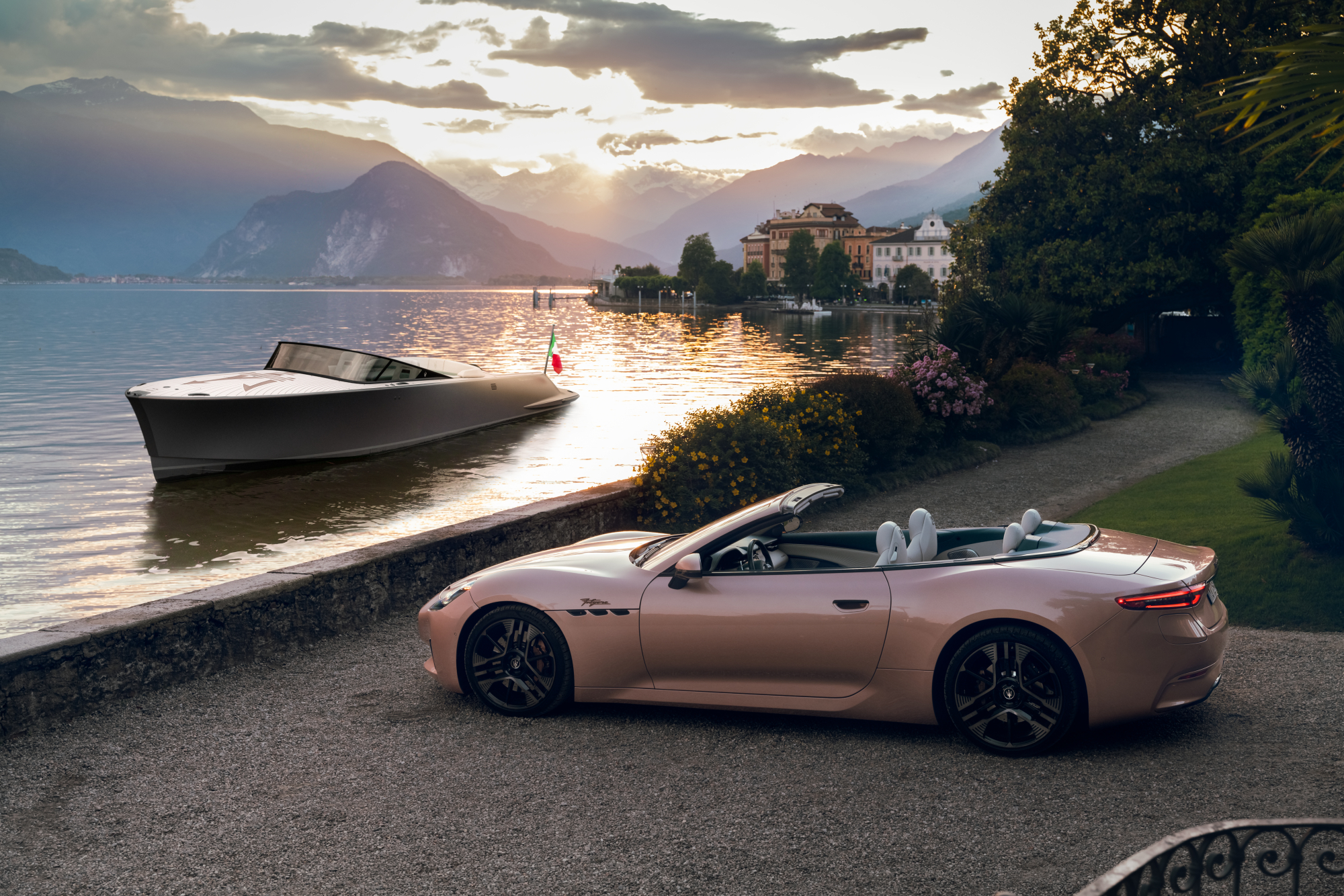 A Maserati GranCabrio Folgore in the foreground with a Maserati TRIDENTE luxury all-electric power boat on Lake Maggiore.