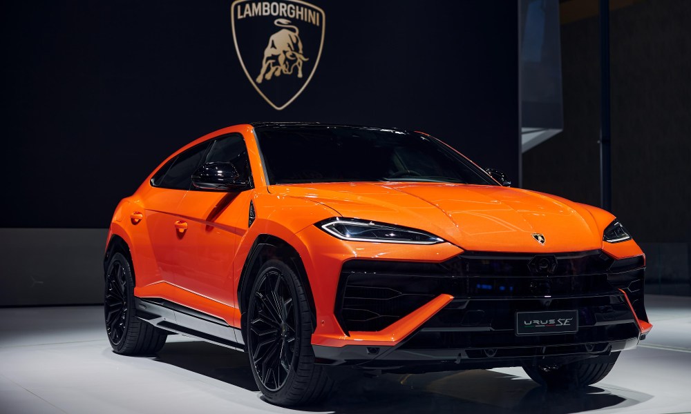 Lamborghini URUS SE on display on stage in a white spotlight.