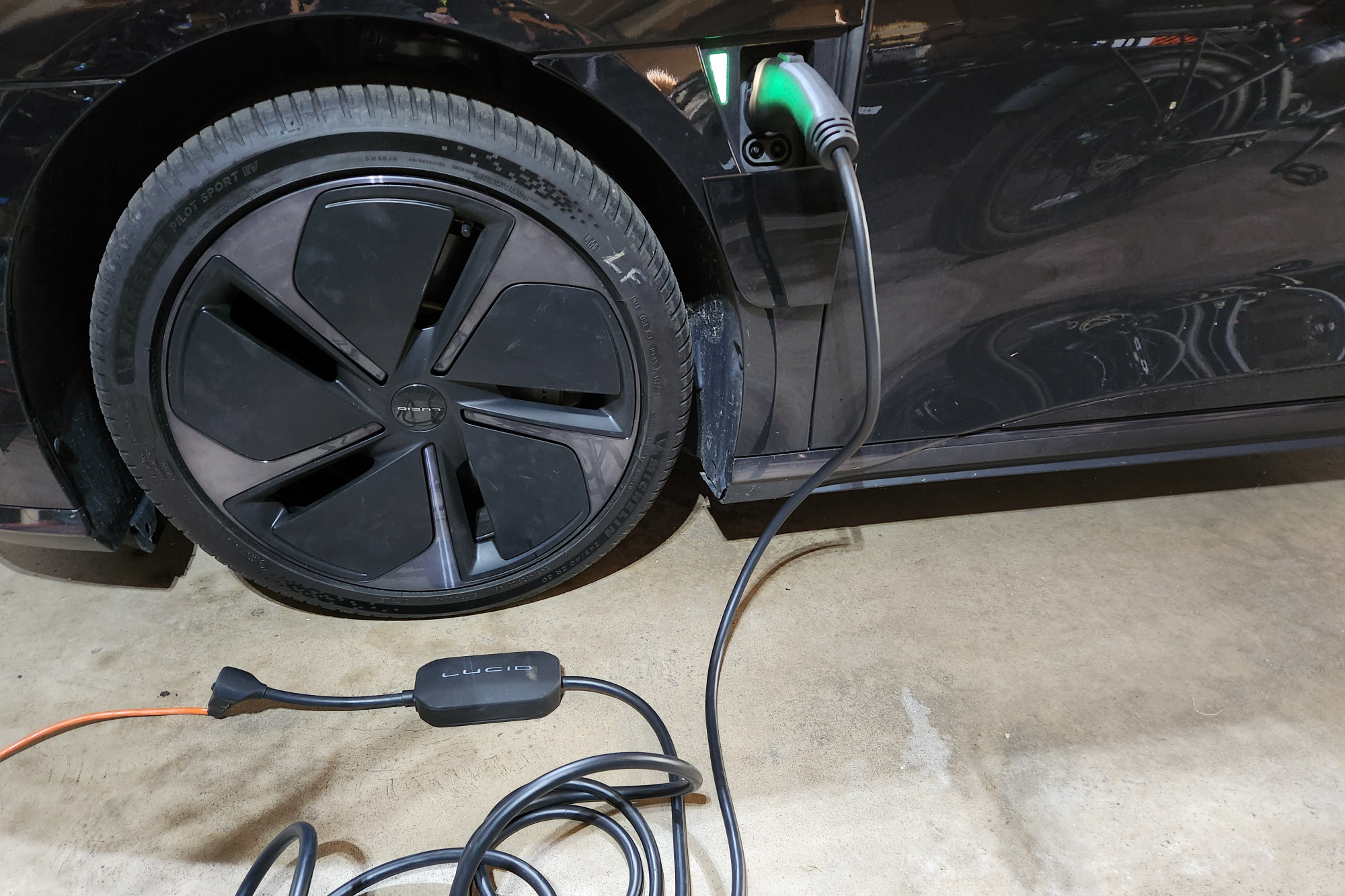 Lucid Air Touring EV charging on 110-120V home outlet with standard cable and adapter.