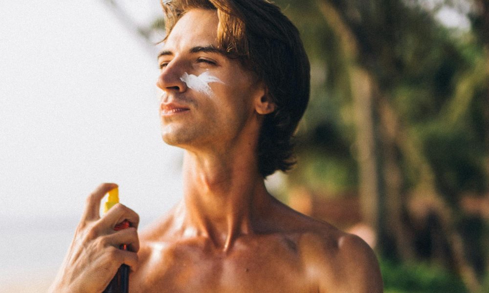 Man spraying on sunscreen outdoors