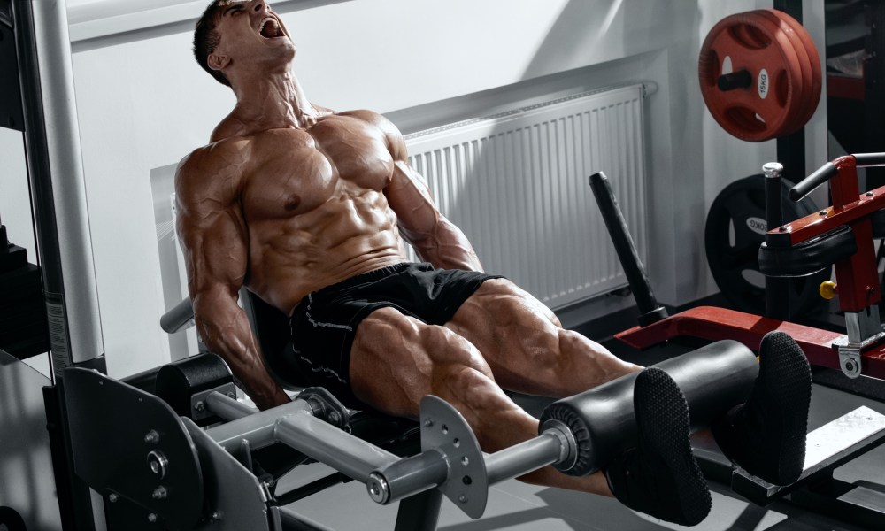 Man doing leg curl exercise on gym seated machine